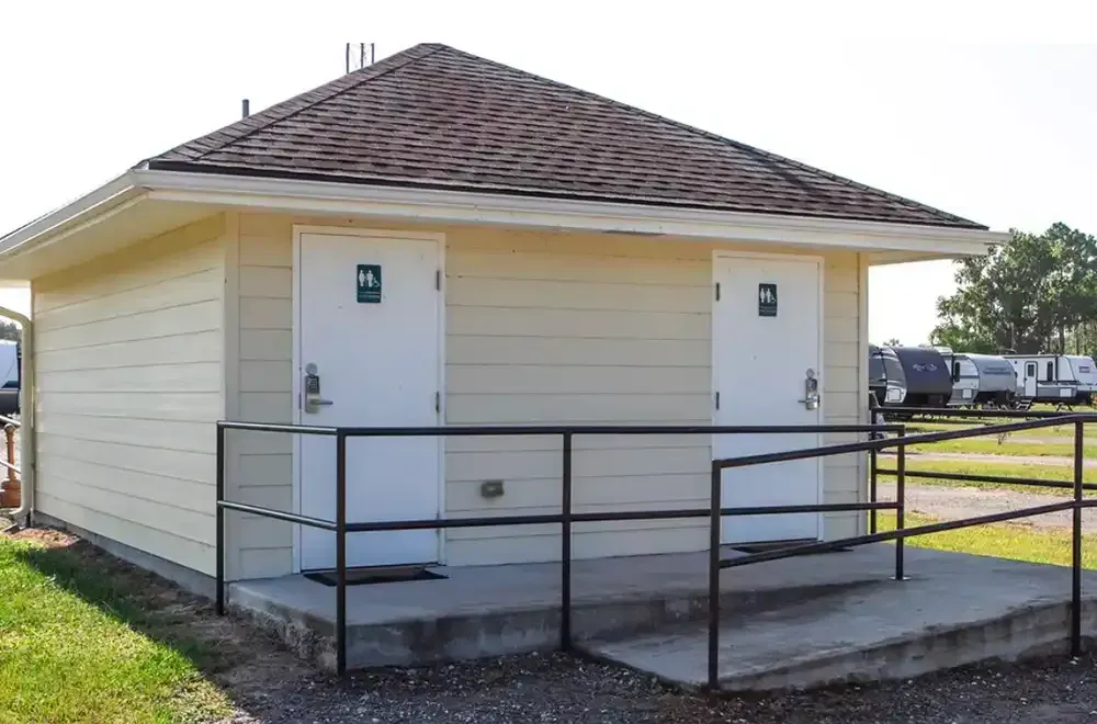Public restroom with two doors, tan siding, brown roof, and ramp.