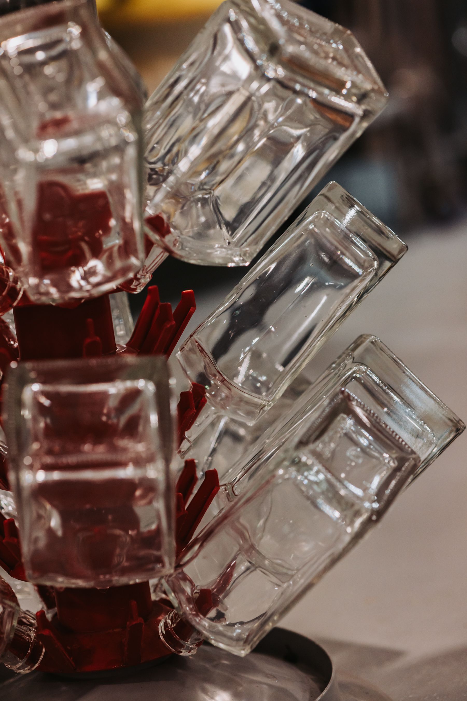 Clear glass cups stacked on a red, tilted drying rack.