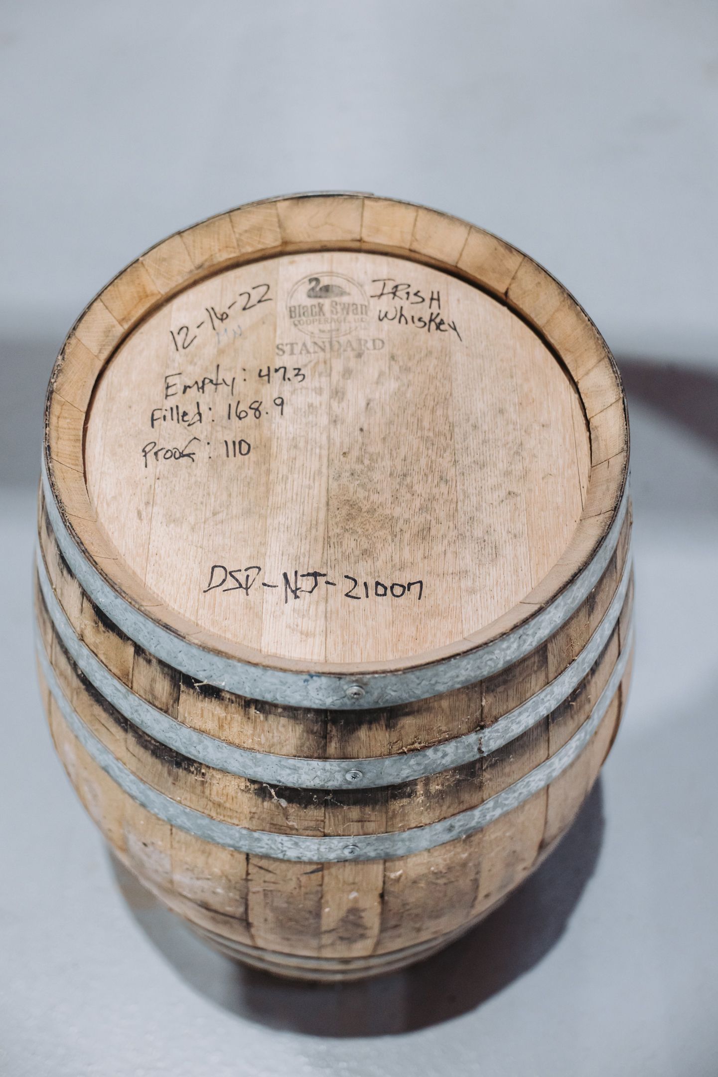 Wooden barrel with metal bands and handwritten text on top.