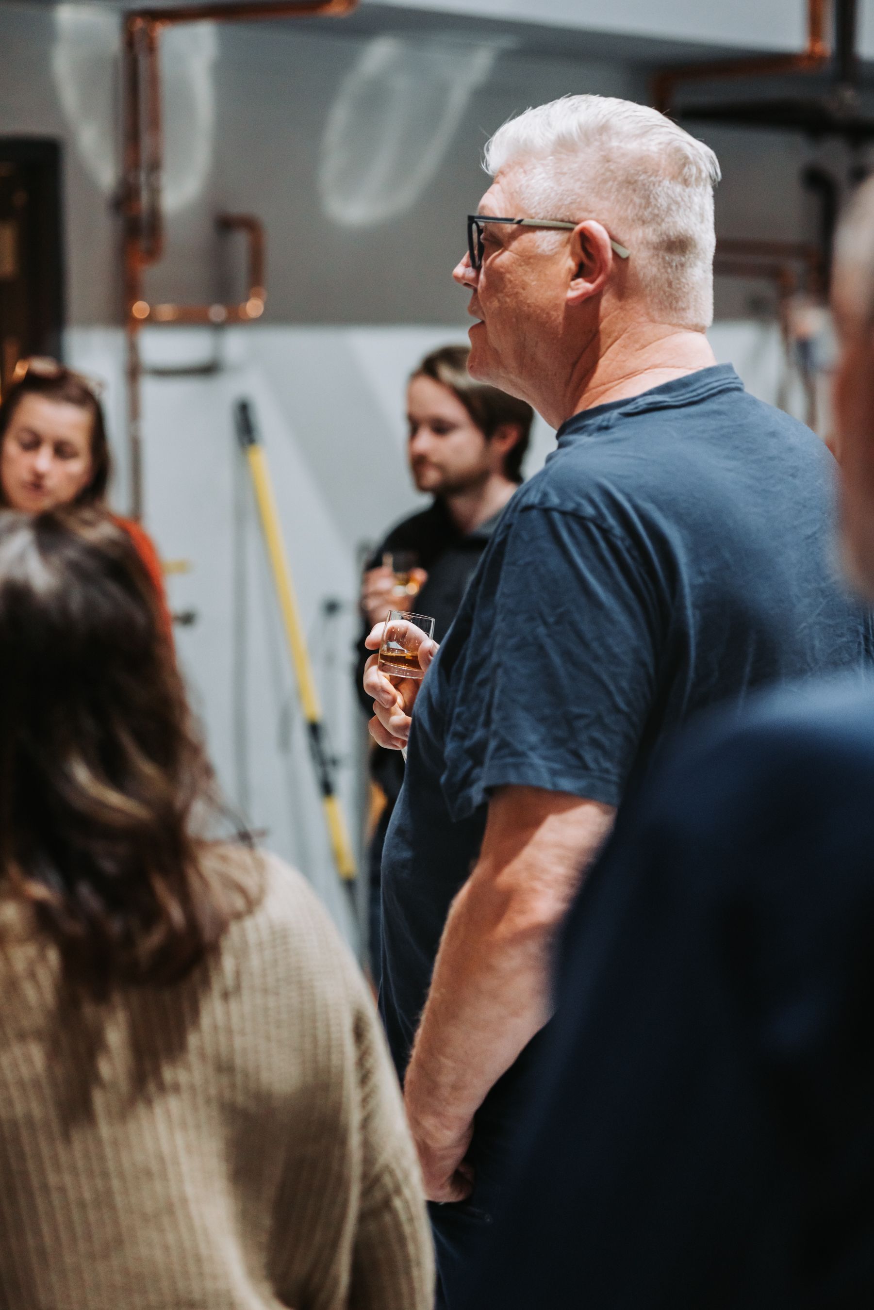 Man with glasses speaking to a group in an industrial setting.