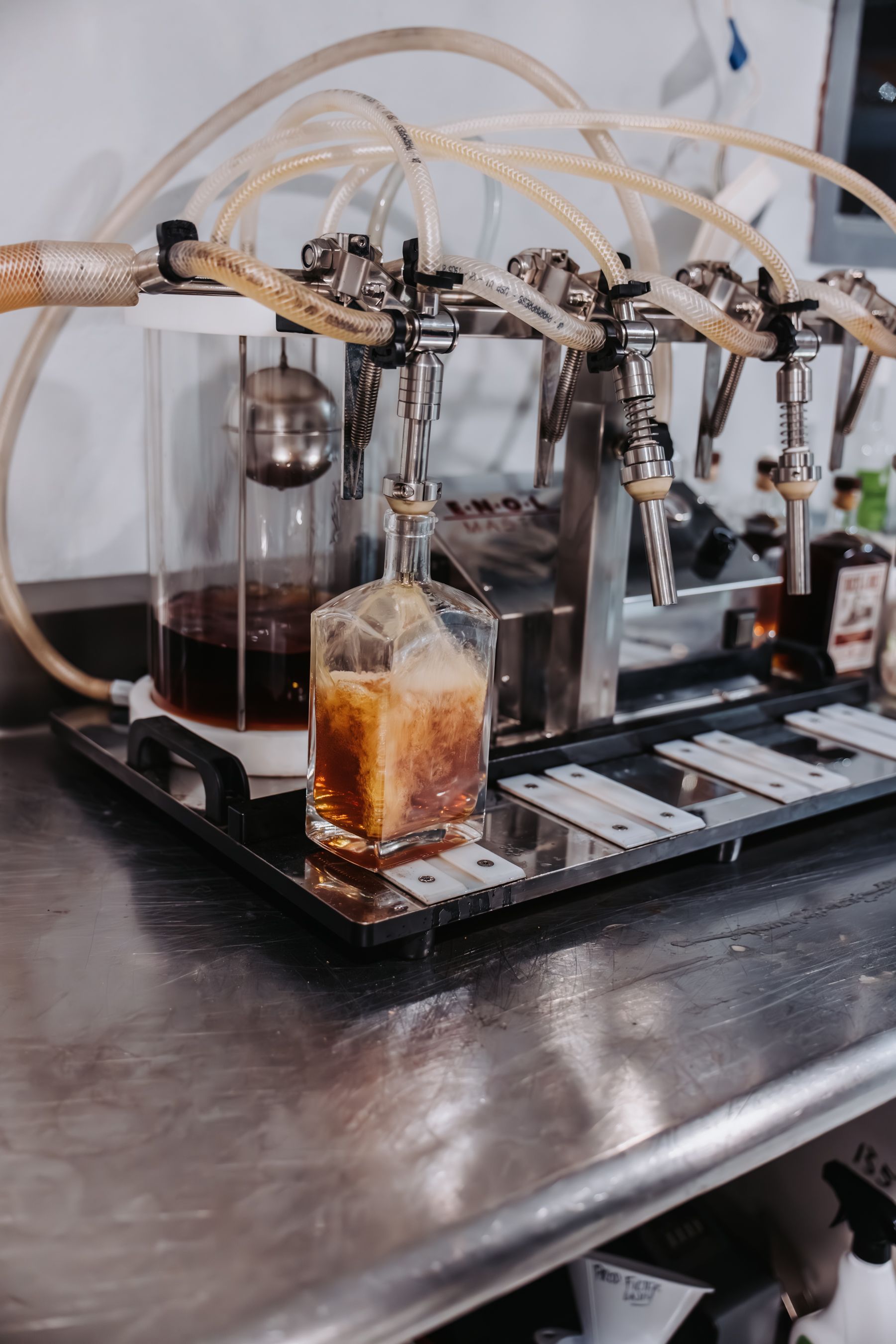 A glass being filled with a dark beverage from a tap system on a countertop.