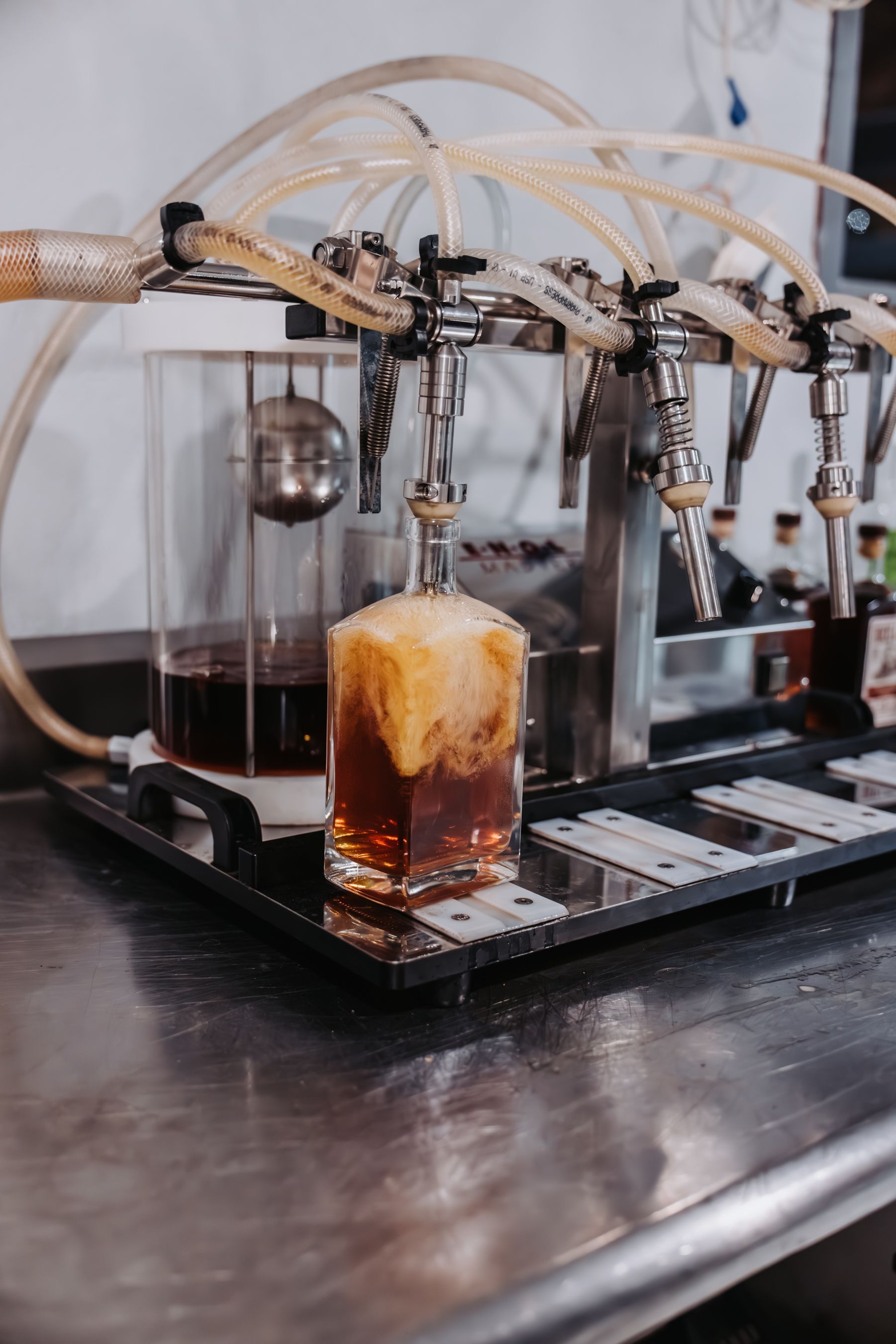 A draft beverage being poured into a square glass from a tap system in a bar.