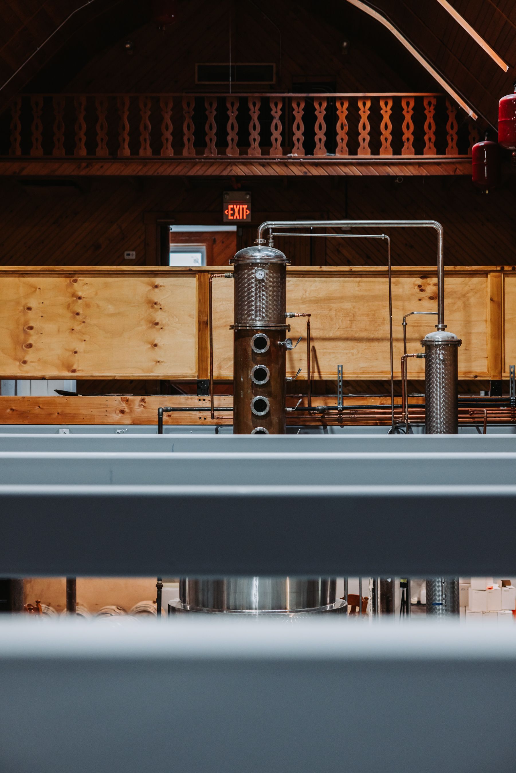 Distillery equipment with copper stills in a building with wooden and brick interiors.