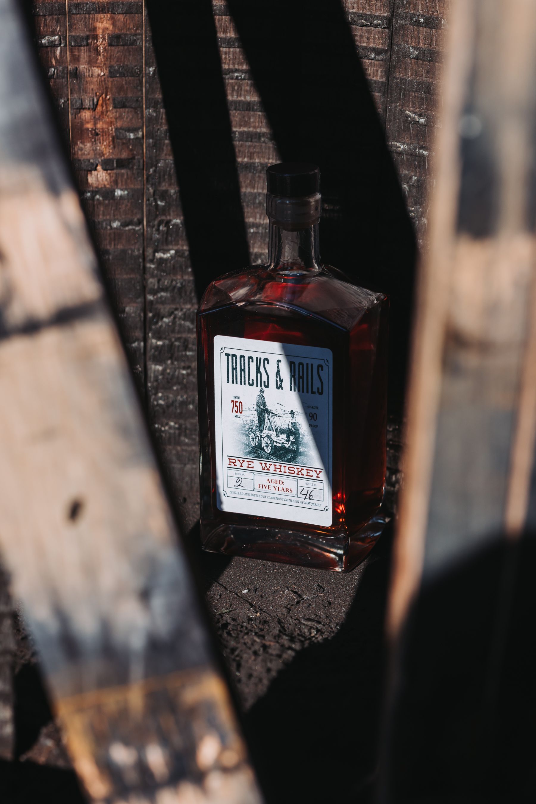 Bottle of liquor with a label, rests on wood planks, dark brown hues.
