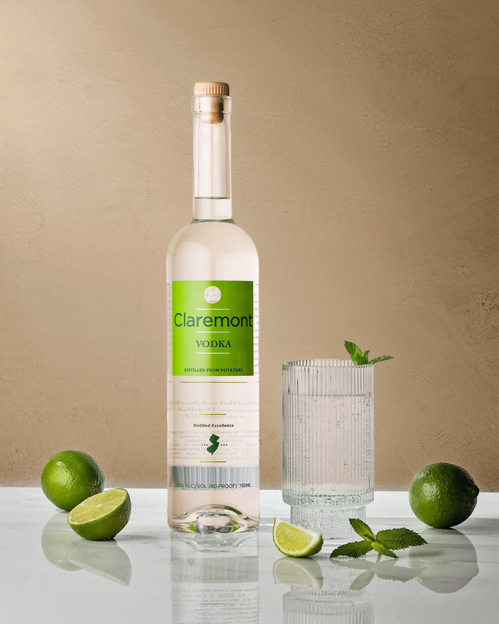 Bottle of liquor, drink in a glass with lime and mint on a white surface, beige background.
