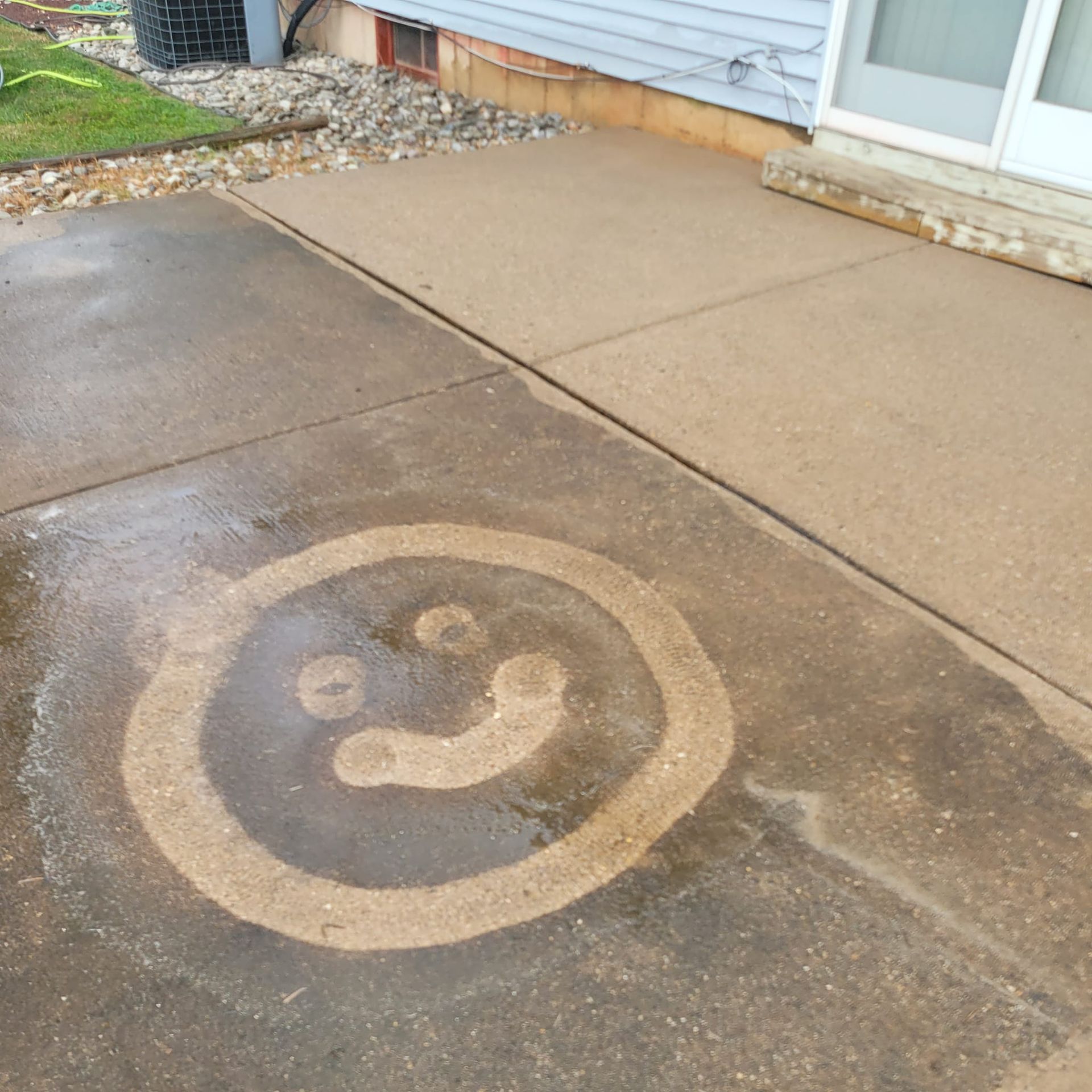 A smiley face is painted on the sidewalk in front of a house