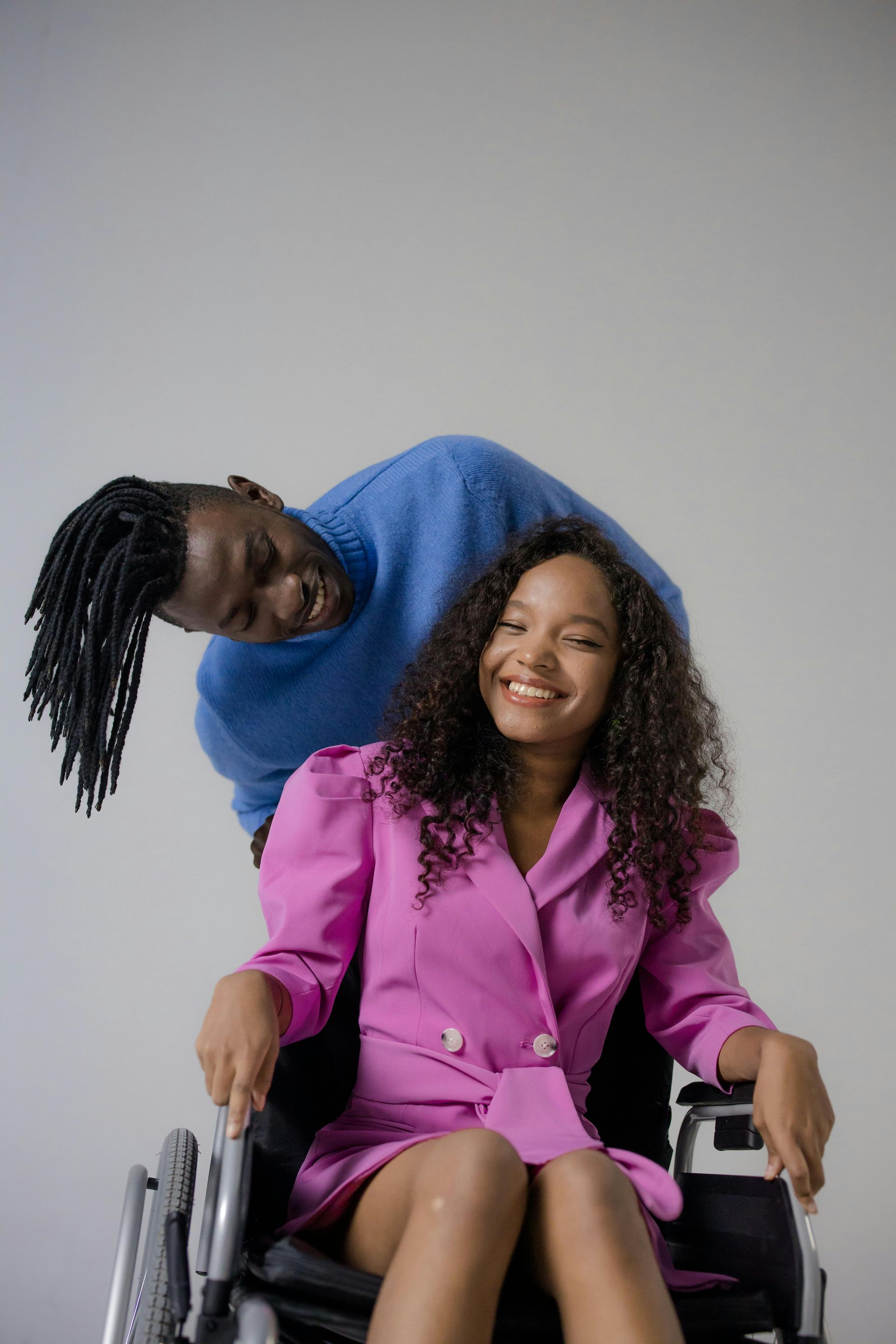A man is sitting on the back of a woman in a wheelchair.
