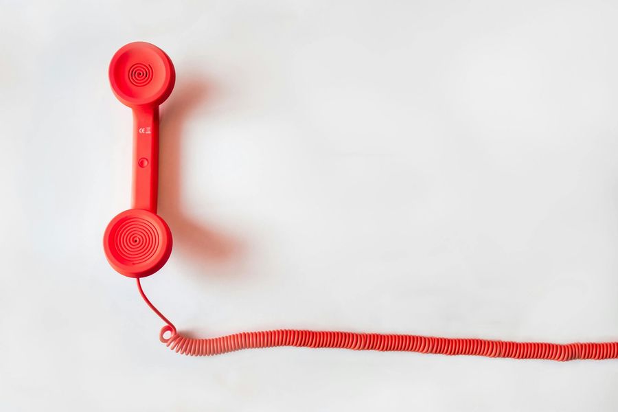 A red telephone with a red cord on a white background.