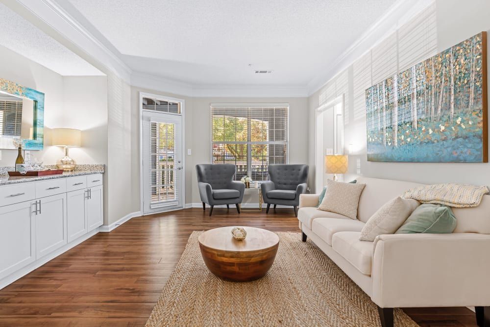 a living room with a couch, chairs, a coffee table, and a painting on the wall at Marquis on Edwards Mill in Raleigh, NC.