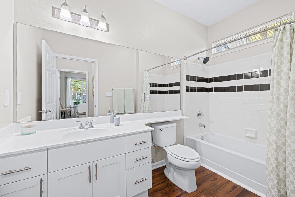 a bathroom with a toilet, sink, tub, and mirror at Marquis on Edwards Mill in Raleigh, NC.
