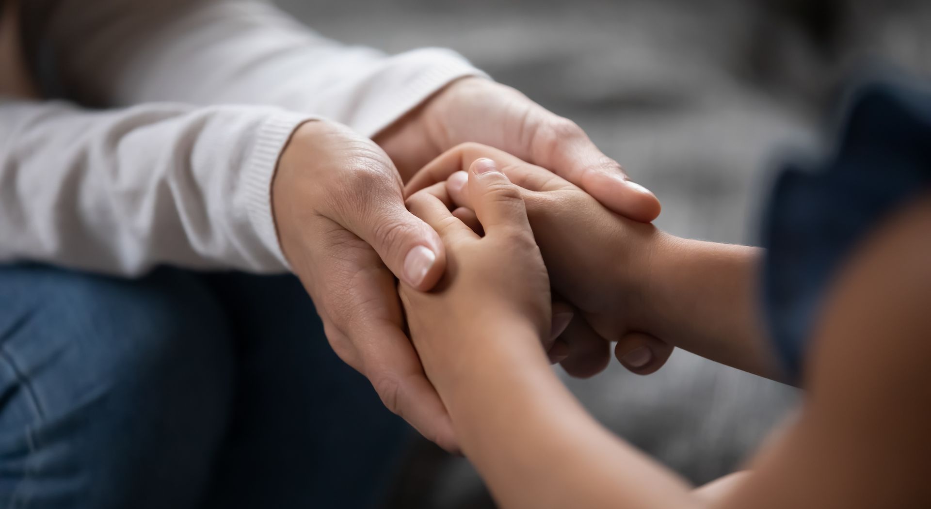 A woman is holding a child 's hand while sitting on the floor.