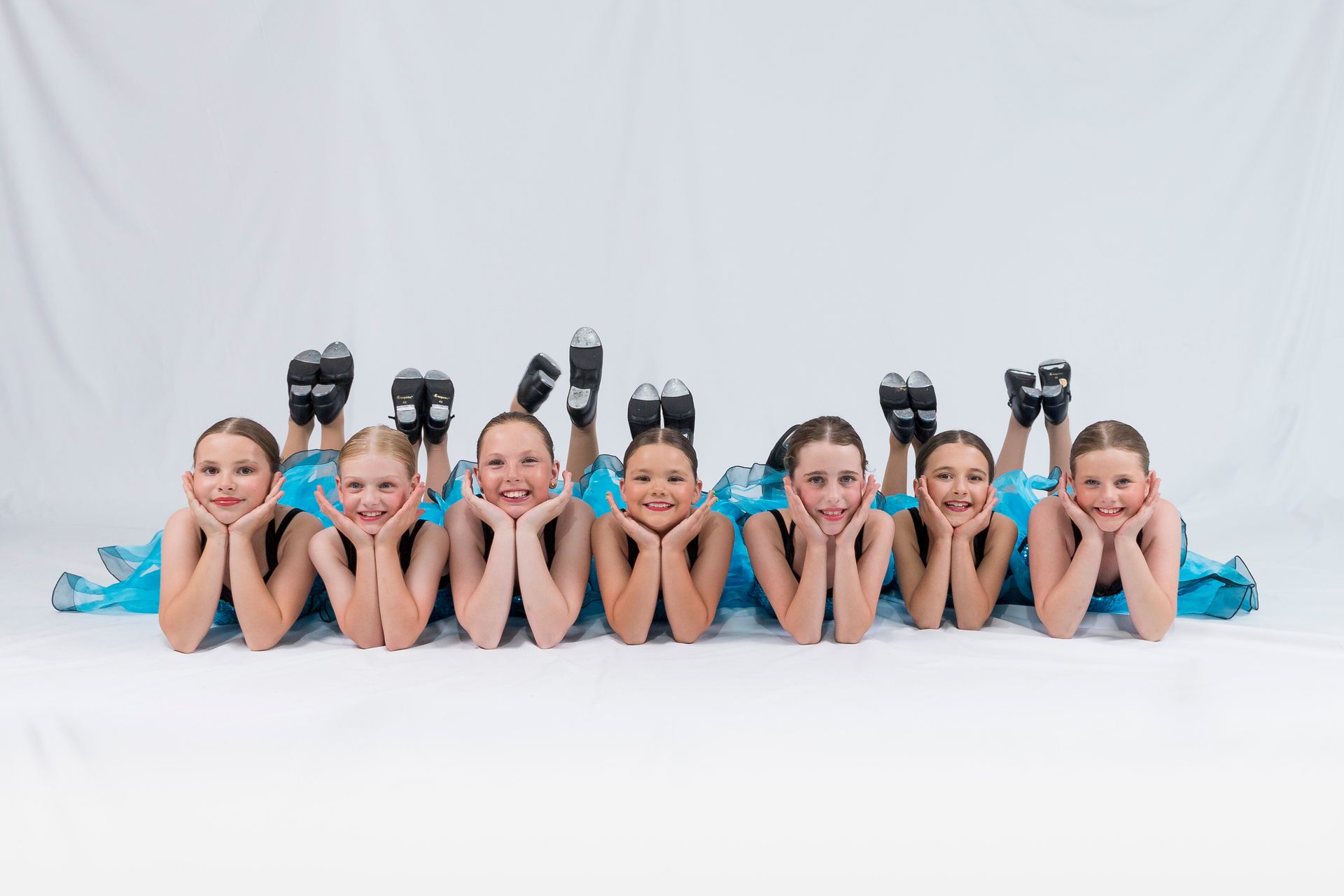 Seven young dancers in bright blue costumes