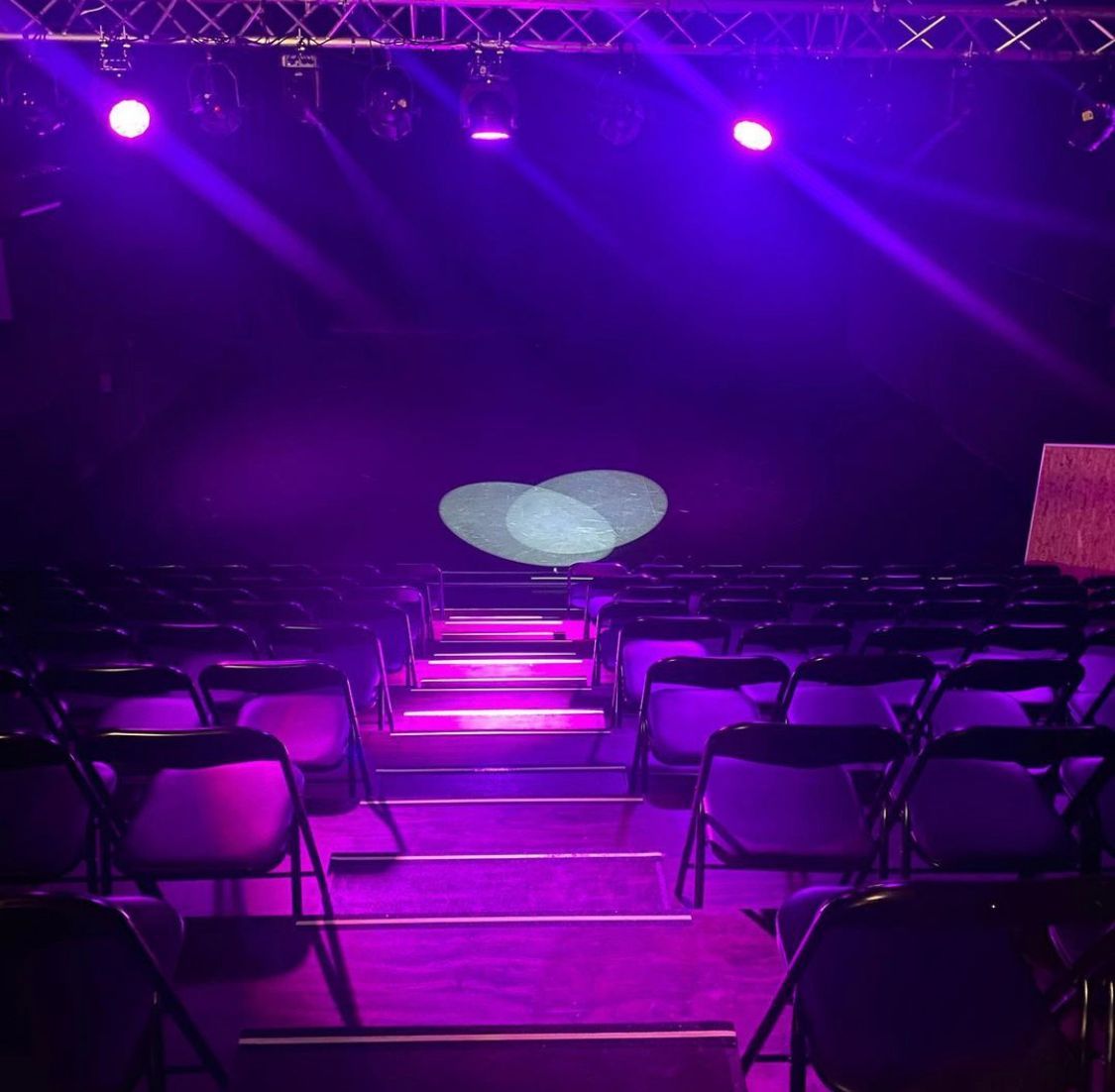 black chairs and a stage illuminated by purple lights,