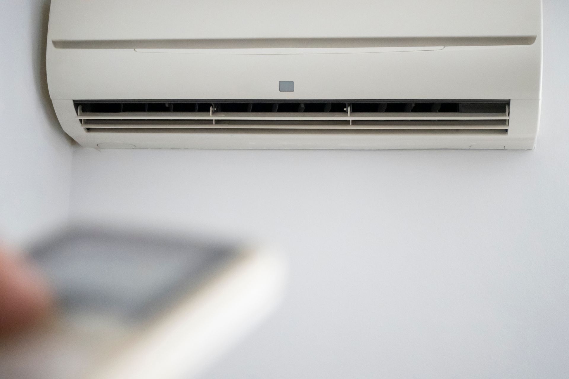 A Person Is Holding A Remote Control In Front Of An Air Conditioner – Sydney, NSW - Leumeah Air Conditioning