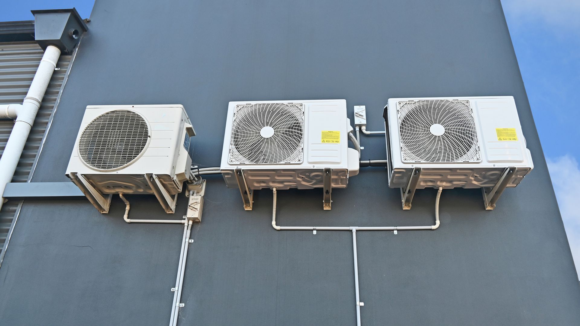 Three Air Conditioners Are Mounted On The Side Of A Building – Sydney, NSW - Leumeah Air Conditioning