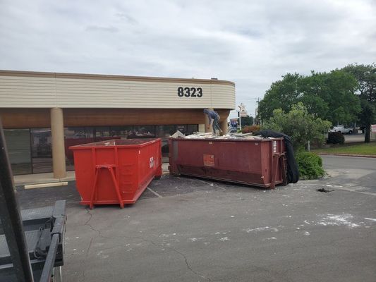 Two shipping containers are parked next to each other on a dirt road.