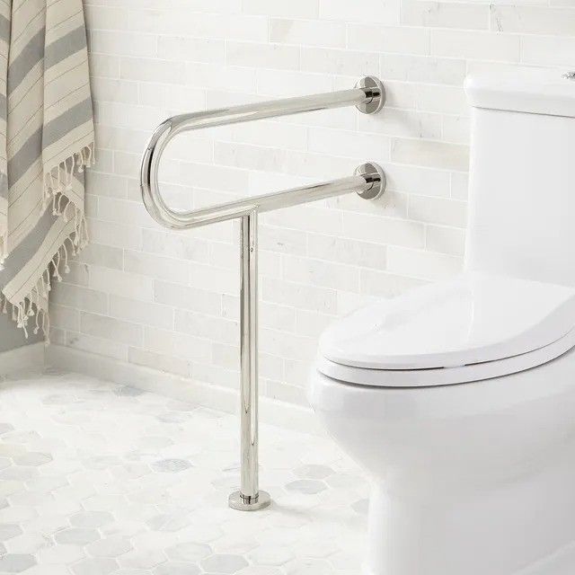 A bathroom with a toilet and a stainless steel hand rail.