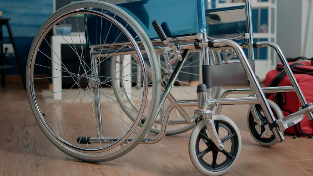 Two wheelchairs are sitting next to each other on a wooden floor.