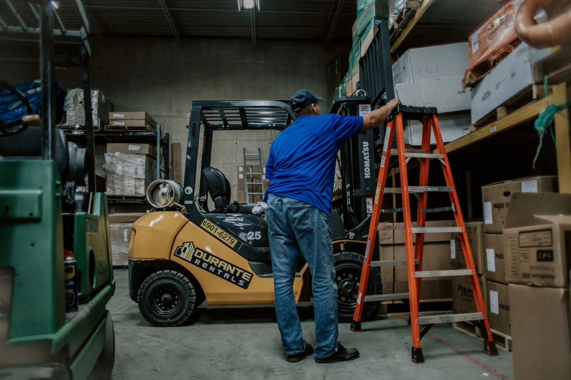 A man is standing next to a forklift in a warehouse.