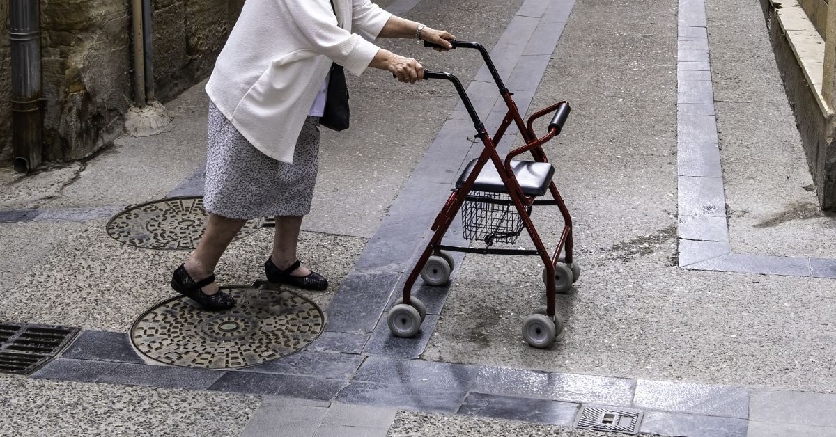 Senior man using an outdoor walker while walking along a waterfront path