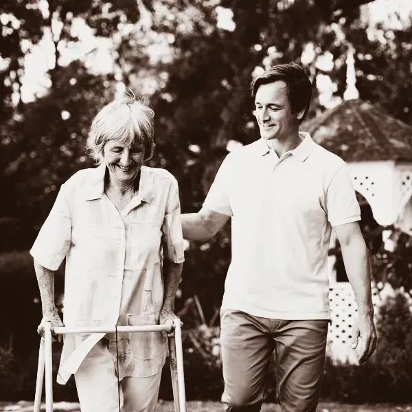 A man is helping an elderly woman walk with a walker