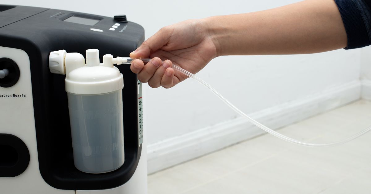 Person connecting tubing to a continuous flow portable oxygen concentrator in a medical setting
