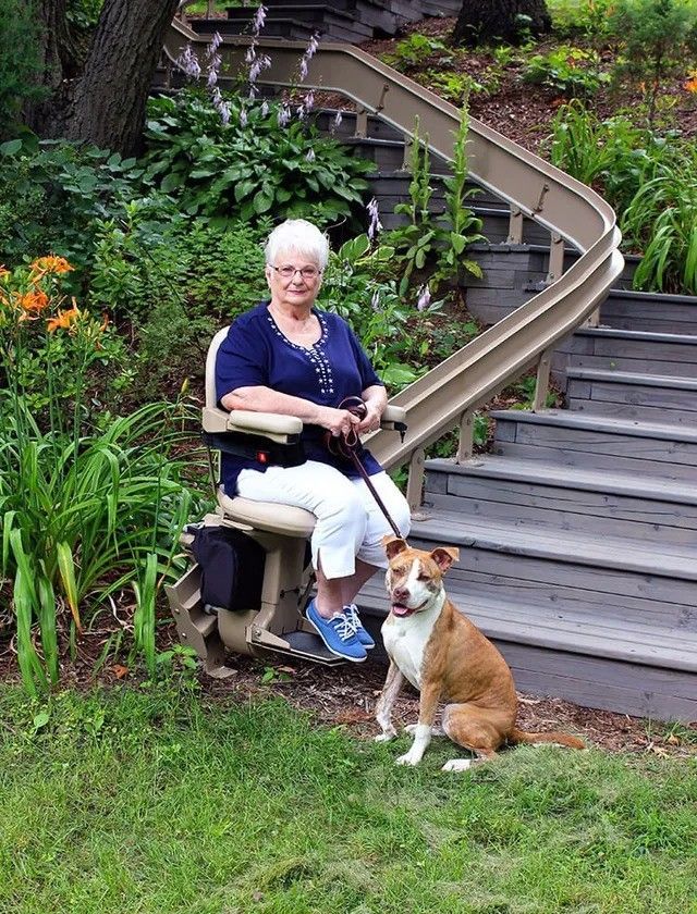 A woman is sitting on a chair next to a dog.