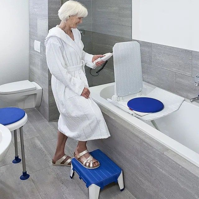 A woman in a bathrobe is standing on a blue step next to a bathtub
