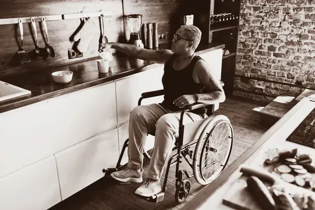 A man in a wheelchair is sitting in a kitchen.