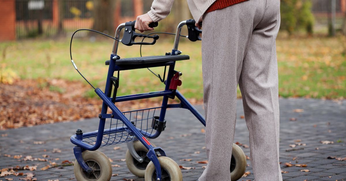 Senior using an outdoor walker on a park pathway for safe and stable mobility