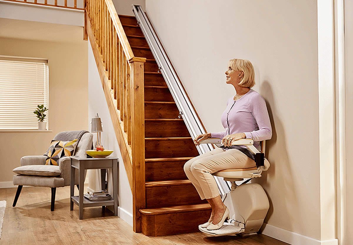 A woman is sitting on a stair lift in a living room.