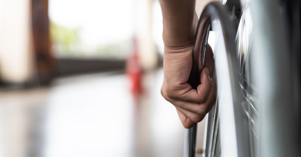 Close-up of a patient gripping a wheelchair wheel for mobility and balance.