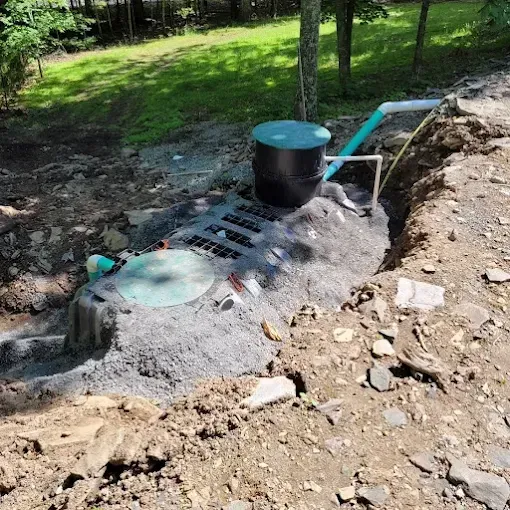 An outdoor septic tank system with two green access ports set in a dirt excavation site.
