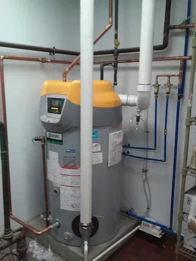 A grey and yellow A. O. Smith water heater with white PVC venting pipes and copper plumbing in a utility room.