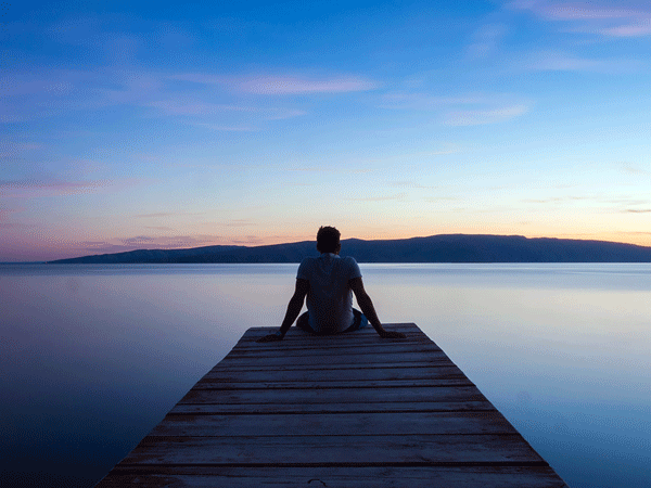 Person sitting on a dock near a lake