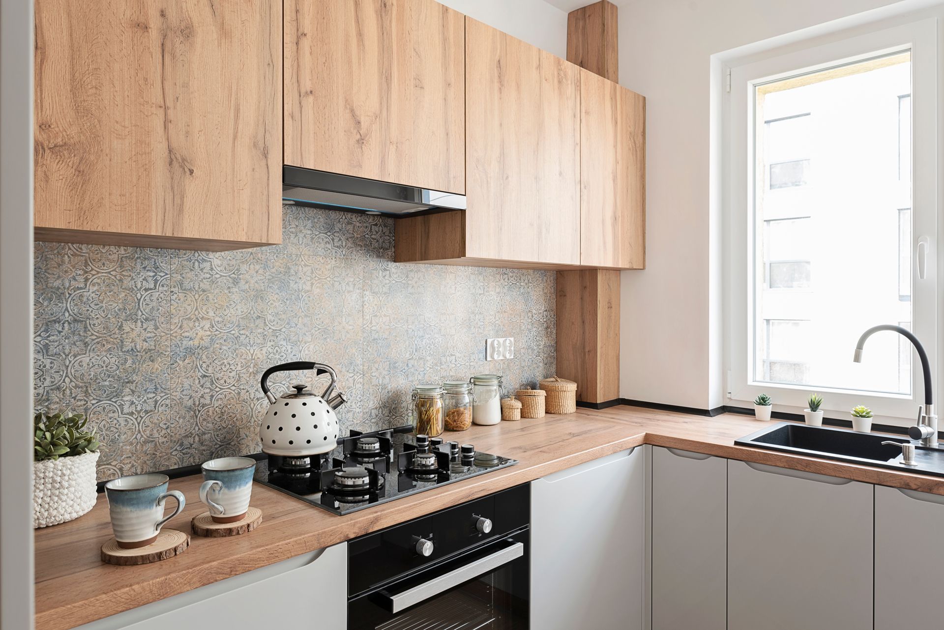 A kitchen with wooden cabinets , a stove , a sink , and a window.