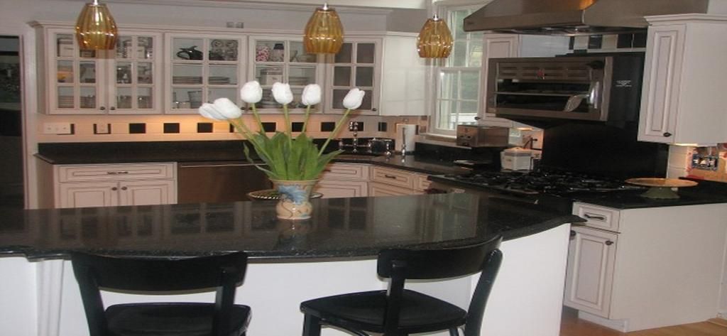 A kitchen with black counter tops and white cabinets