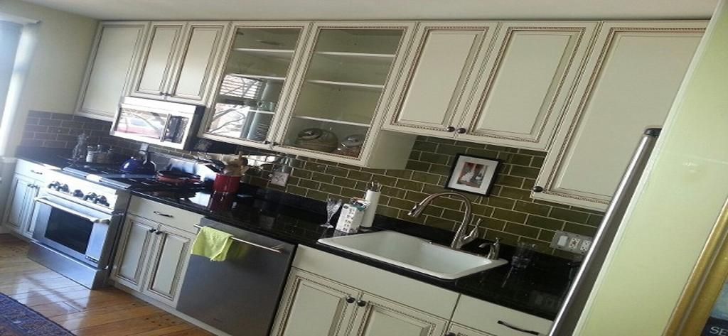 A kitchen with white cabinets and black counter tops