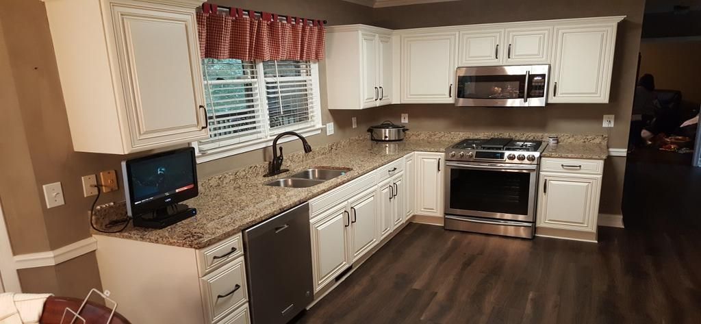 A kitchen with white cabinets , granite counter tops , stainless steel appliances and a computer on the counter.
