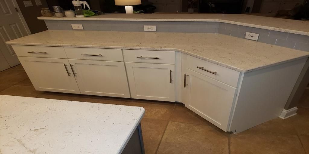 A kitchen with white cabinets and granite counter tops.