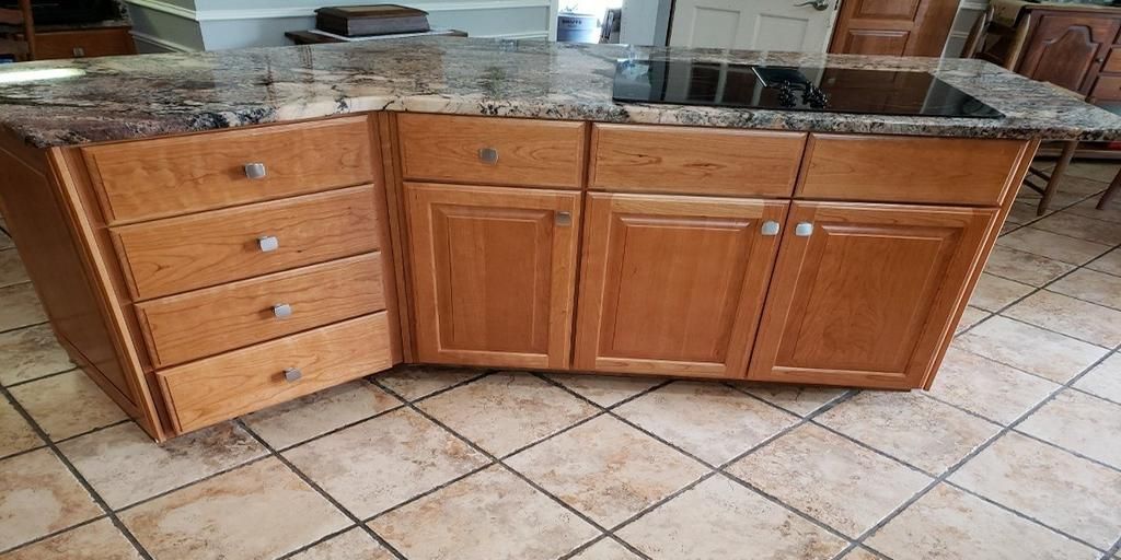A kitchen island with wooden cabinets and granite counter tops.
