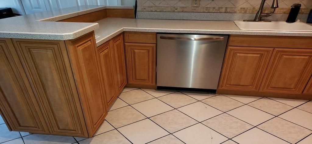 A kitchen with wooden cabinets and a stainless steel dishwasher.