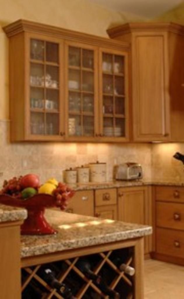 A kitchen with a wine rack and a bowl of fruit on the counter