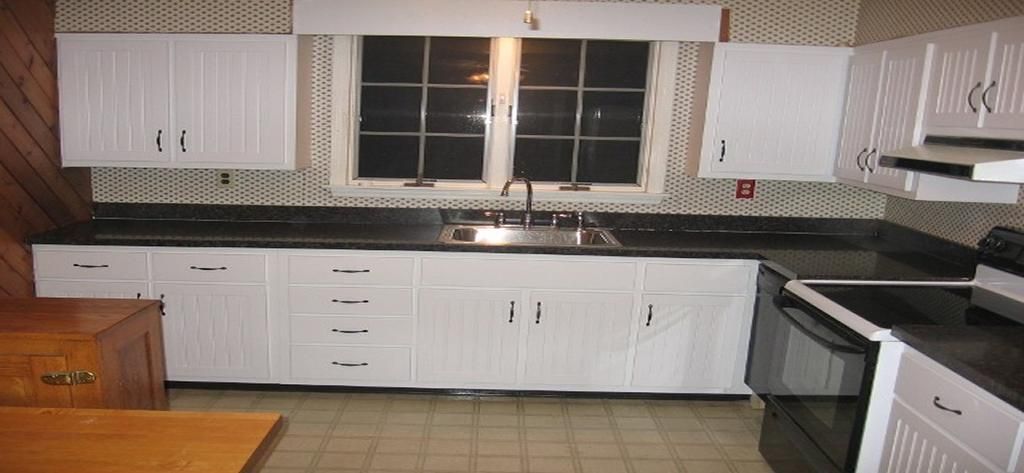 A kitchen with white cabinets and black counter tops