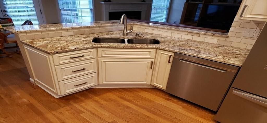 A kitchen with granite counter tops , stainless steel appliances , and white cabinets.