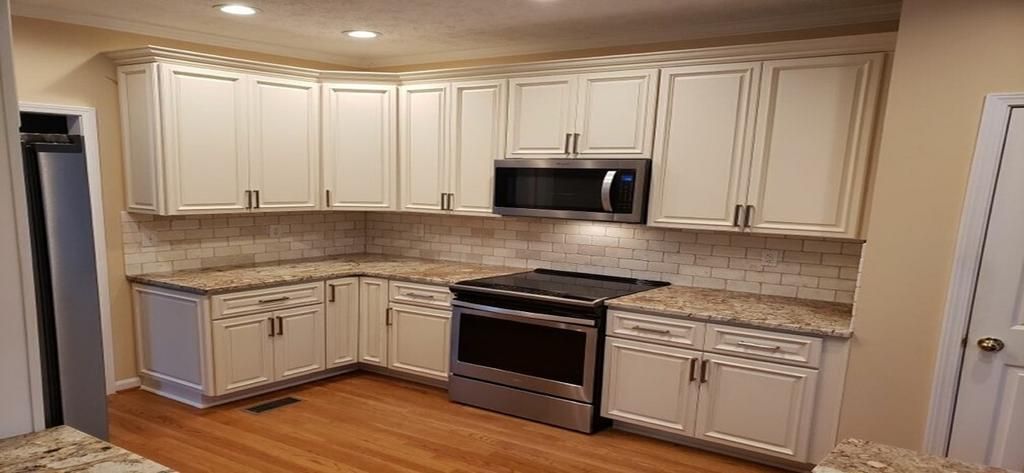 A kitchen with white cabinets , granite counter tops , stainless steel appliances and a stove.
