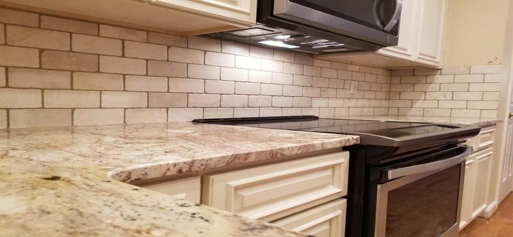 A kitchen with a stove , microwave , and granite counter tops.