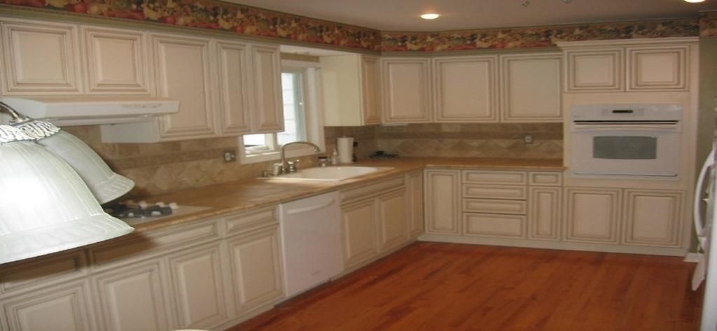 A kitchen with white cabinets and hardwood floors.