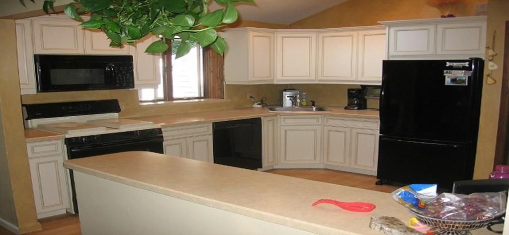 A kitchen with white cabinets and a black refrigerator