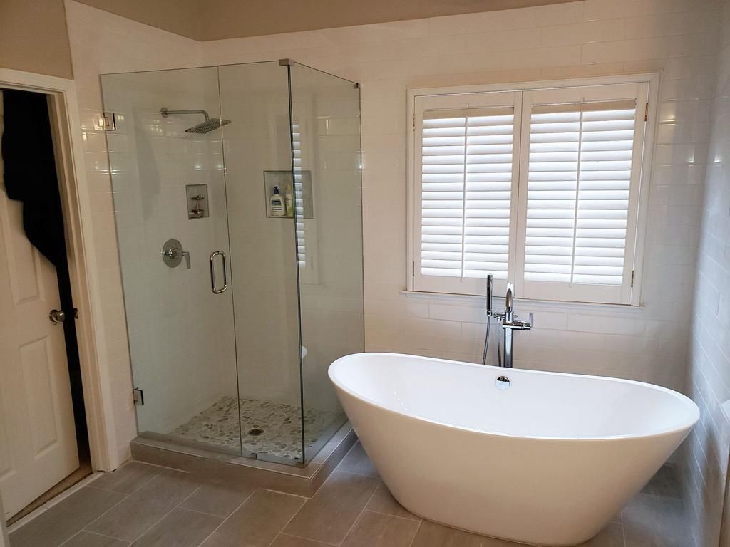 A bathroom with a tub , shower , and window.